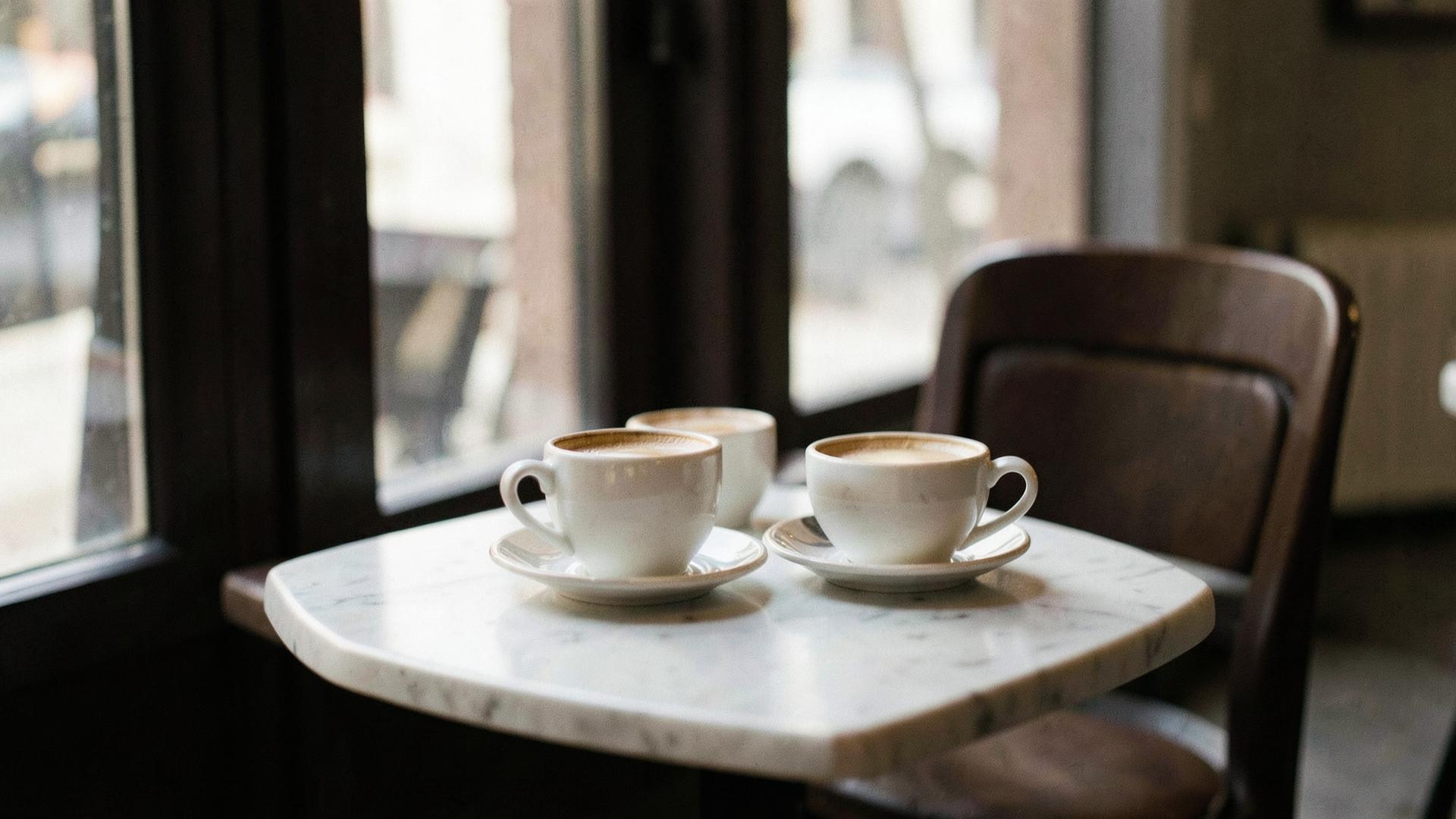 Twee koffiekopjes op een cafétafel bij zacht daglicht